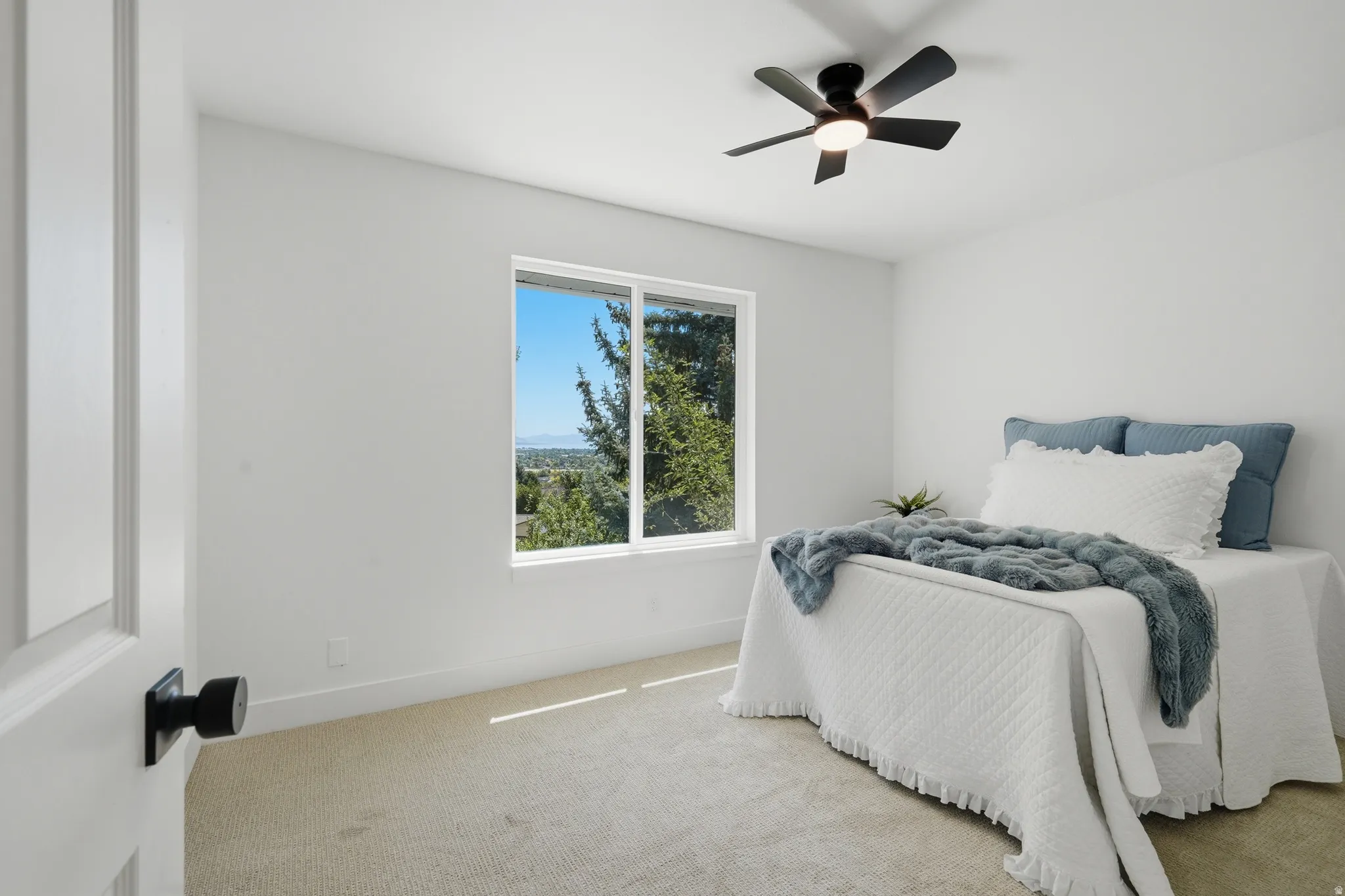 Bright bedroom #2 with incredible views, white walls, and a ceiling fan with integrated lighting