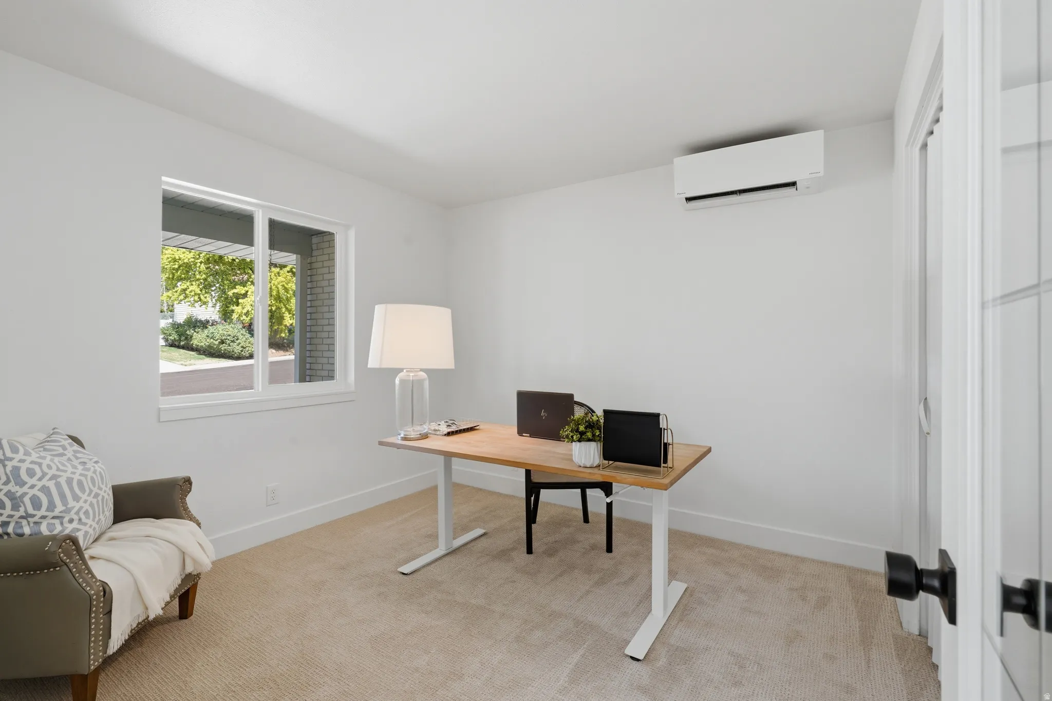 Bedroom 1 (staged as an office) White walls, carpeted flooring, window with mountain views, and a wall-mounted mini-split system
