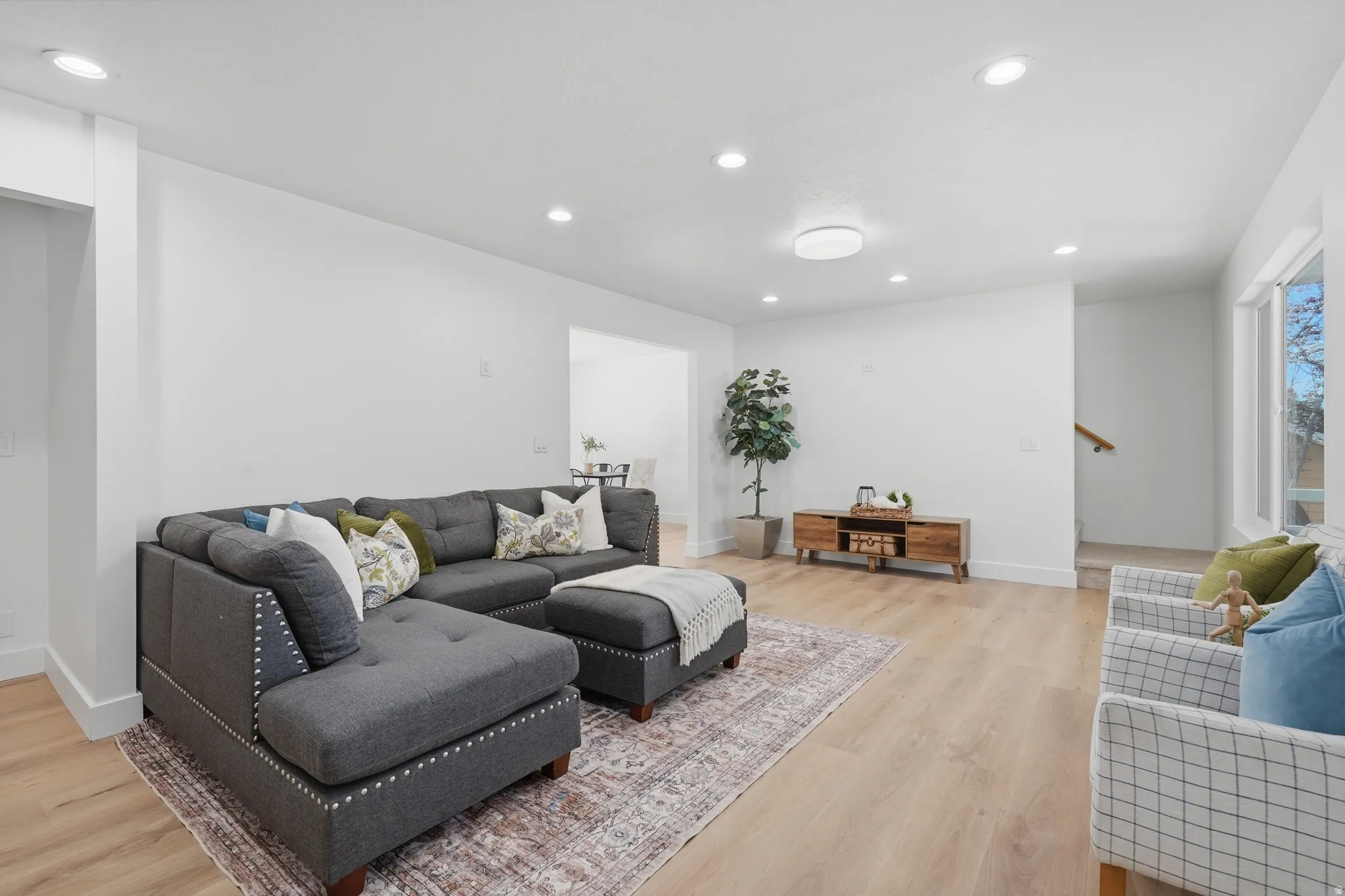 Bright living area featuring wood-finish LVP flooring, recessed lighting, and large windows