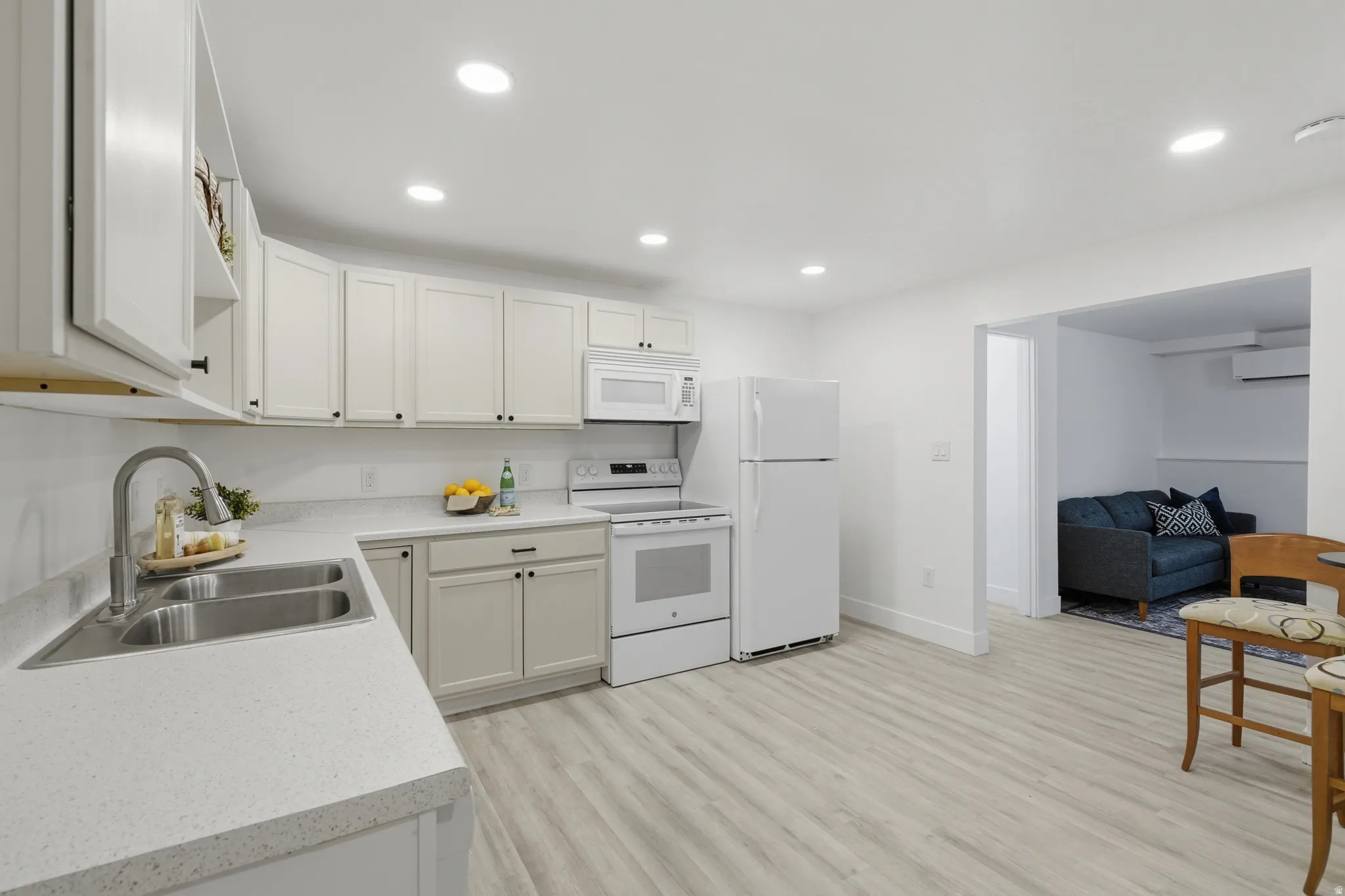 ADU kitchen featuring light cabinetry, and countertops, a double basin sink with a high-arc faucet, and wood-finish laminate flooring