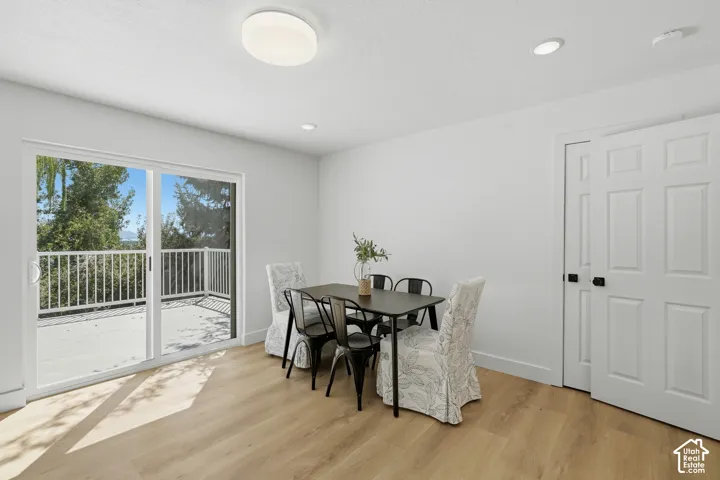 Light wood-finish LVP flooring, white walls, and a sliding glass door leading to an outdoor deck with valley views
