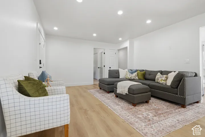 Open living area featuring light wood-finish LVP flooring and recessed lighting
