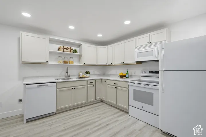 ADU kitchen with recessed lighting, wood-finish laminate flooring, light cabinetry, integrated stainless steel sink, and white appliances