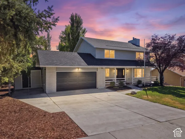 Two-story residence featuring light gray siding, a dark gray shingle roof, a two-car garage with a dark gray door, and light brick accents