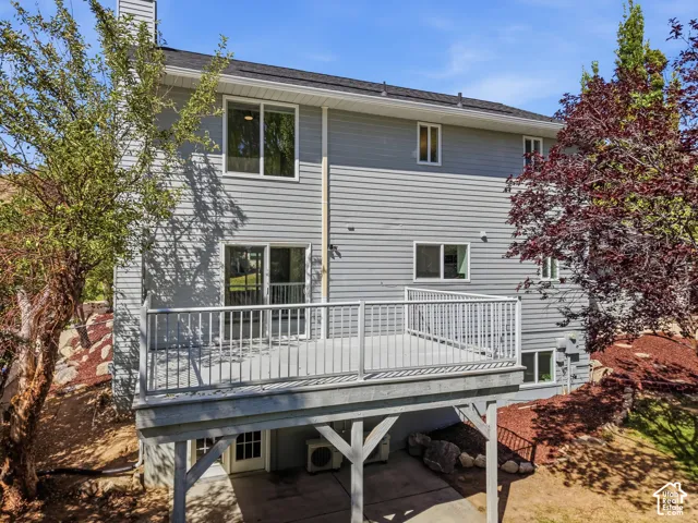 Exterior featuring light gray siding, a dark shingle roof, and a raised composite deck with white railings