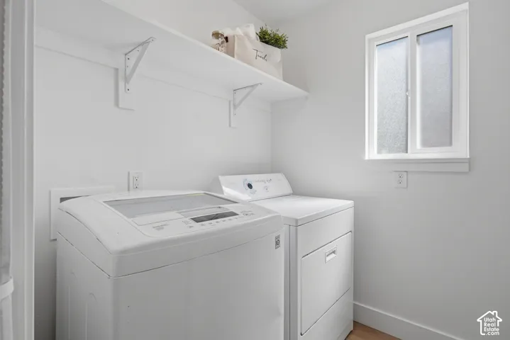 Laundry area with white walls, wood-finish LVP flooring, and a frosted window