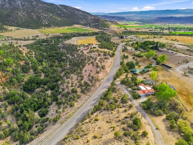 Aerial perspective showcasing a mountain backdrop, verdant valley, and a paved road