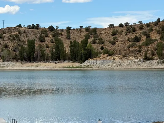 Waterfront access with natural rock shoreline, surrounded by a natural landscape with mature trees and a distant hillside