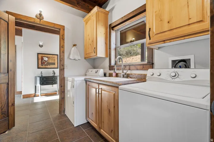Wood-finish cabinetry, tile flooring, and a utility sink with a window