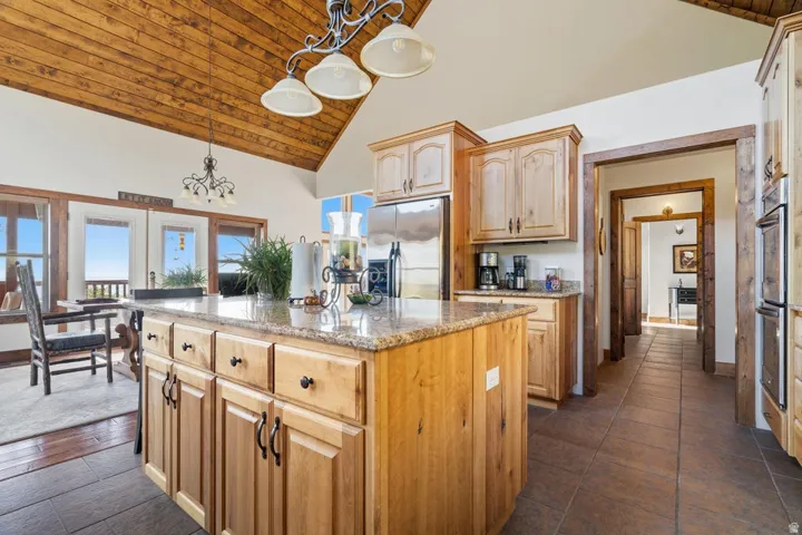 Kitchen featuring a center island with a stone countertop, wood cabinetry, stainless steel appliances, and tile flooring