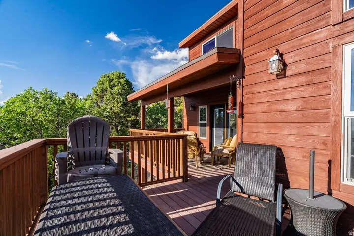 Expansive wood-finish deck with railing, exterior siding, and outdoor wall sconce