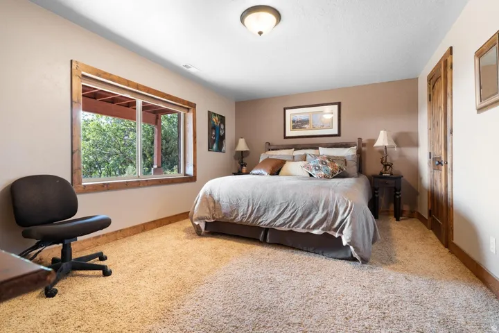 Plush carpeting, wood-trimmed window, and warm wall colors define this room, complemented by a wood-paneled door