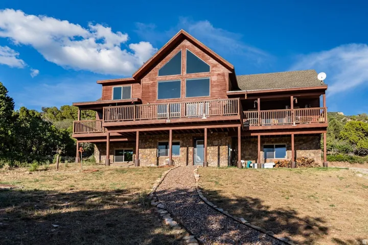Wood-sided exterior with a stone foundation, multiple balconies, and an A-frame window design