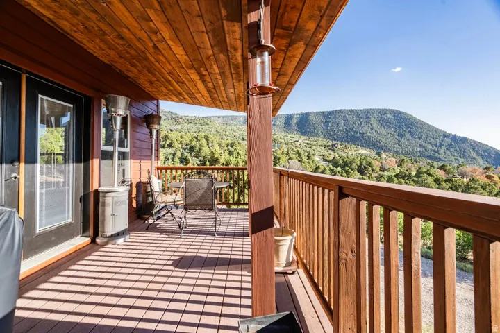 Expansive outdoor deck with wood-finish railing, wood panel ceiling, and mountain scenery
