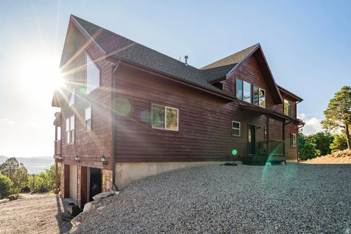 Multi-level residence featuring a wood-panel exterior, a pitched roof, and a gravel driveway