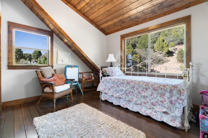 Vaulted wood-paneled ceiling with exposed beams, wood-finish flooring, and large windows with natural wood trim