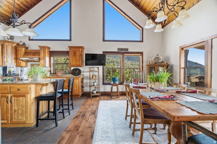 Vaulted wood-finish ceiling, natural wood cabinetry, stone countertops, wood-finish flooring, and expansive windows