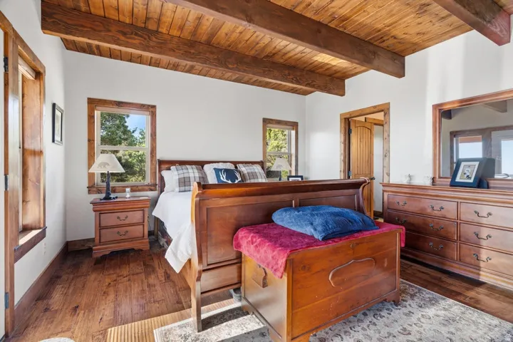 Wood-finish flooring, exposed wood beam ceiling, wood-trimmed windows, and solid wood interior doors