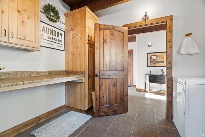Utility room featuring light wood cabinetry, a built-in counter, a dark wood paneled door, and a hanging clothes rod