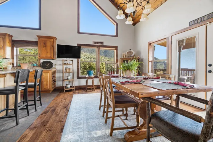 Vaulted wood-paneled ceiling, exposed beam, wood-finish flooring, wood cabinetry, and large windows