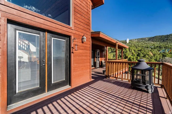 Expansive outdoor deck with wood-finish railing, a covered porch area, and a large upper window