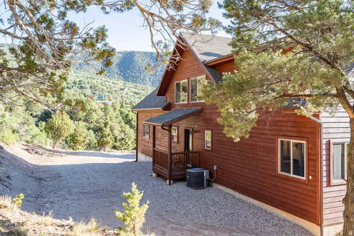 Wood-sided exterior with multiple windows, covered entry, and gravel driveway