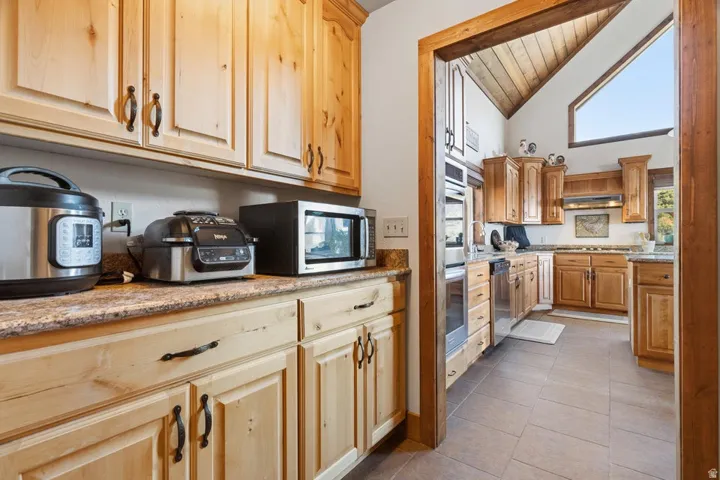 Kitchen featuring natural wood cabinetry, light-toned countertops, and tile flooring