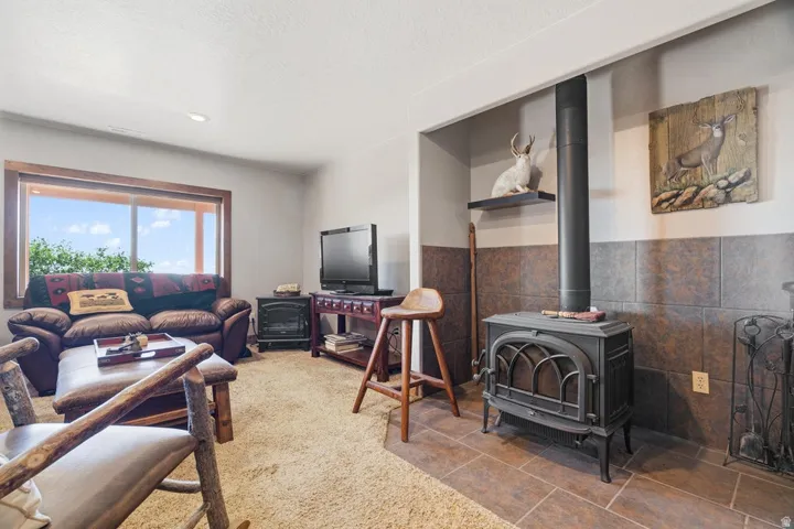 Spacious living area featuring a prominent wood-burning stove with a black stovepipe, tile flooring, and a large window