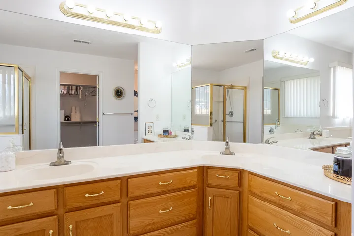Dual vanity with solid surface countertops, wood-finish cabinetry, and individual basin sinks