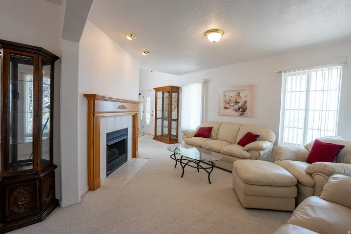Living area featuring a fireplace with a wood mantle, a tiled hearth, recessed lighting, and a front entry door with decorative glass