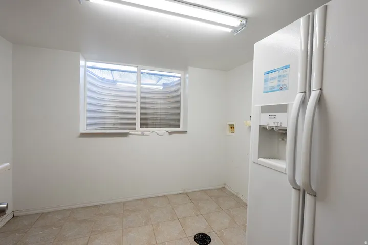 White walls, tiled flooring, fluorescent lighting, and a basement window