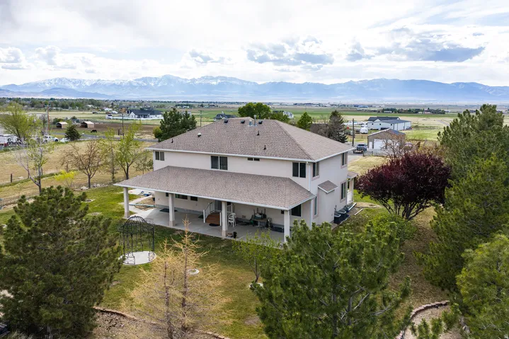 Expansive property featuring a two-story residence, a covered patio, and a vast surrounding landscape
