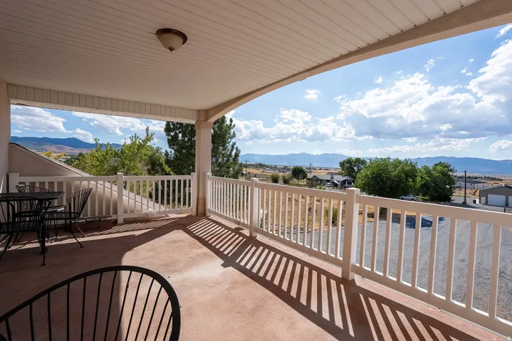 Covered balcony featuring a white railing, a ceiling-mounted light fixture, and distant mountain scenery