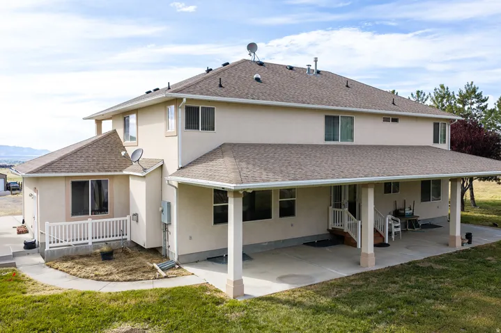 Expansive rear exterior featuring a covered patio, multiple windows, and a separate side patio with a white railing