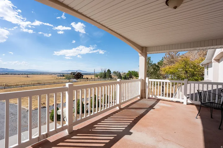 Expansive covered deck featuring a white railing and a wide open sky