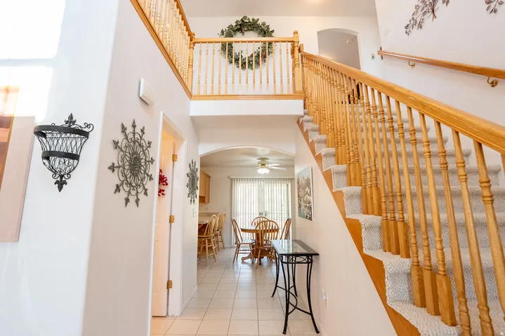 Two-story entryway with tile flooring, wood-finish staircase, and upper-level landing