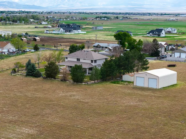 Two-story property with a covered porch, mature trees, and a detached two-door metal building
