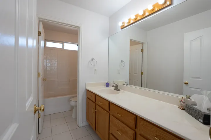 Vanity with wood-finish cabinetry, solid surface countertop, and an integrated basin sink