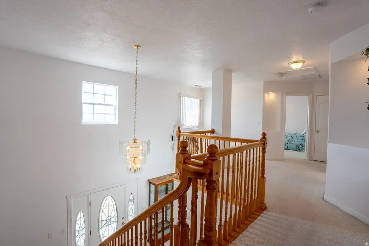 Two-story foyer with a tiered chandelier, transom window, and wood banister