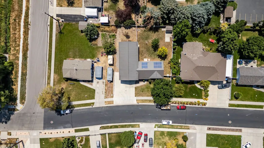 Solar panel array, paved driveway, mature trees, manicured lawns, and asphalt roadways