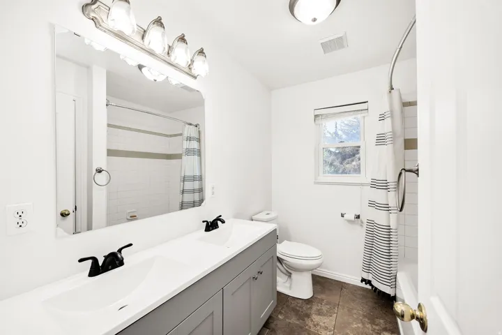 Dual vanity with matte black fixtures, white countertop, and gray cabinetry
