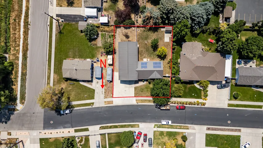 Aerial perspective showcasing a property with a paved driveway, mature trees, and a defined lot boundary