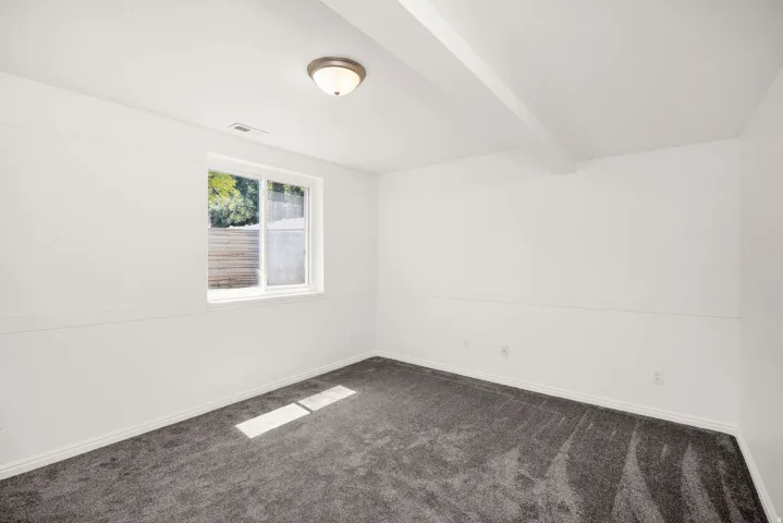 Bright room with white walls, a single window, and dark gray carpeting