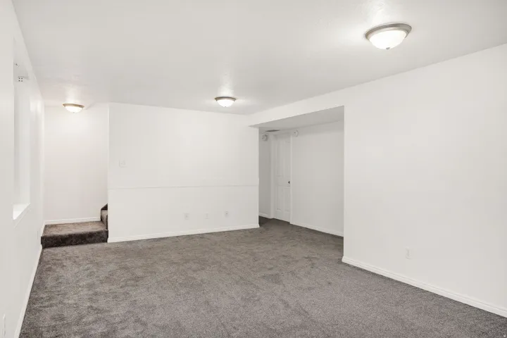 Spacious room featuring gray carpet flooring, white painted walls, and ceiling-mounted flush light fixtures