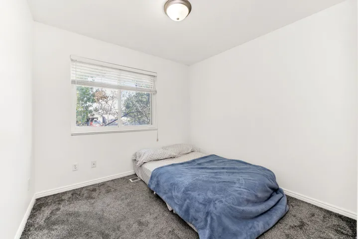 White walls with gray carpeting and a single window