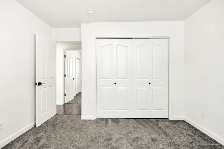 Expansive wall-to-wall carpeting, white interior doors with dark hardware, and a bright white ceiling