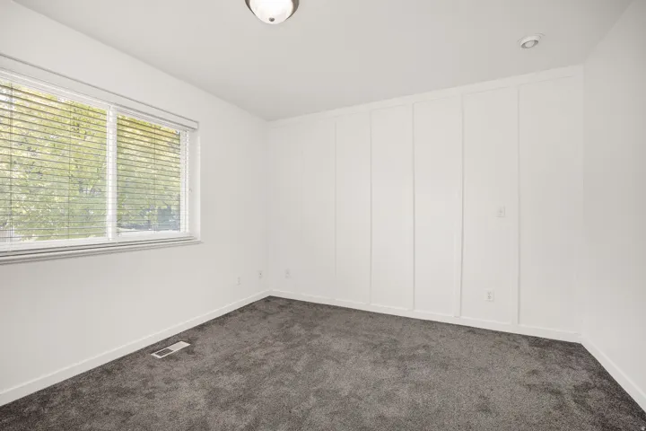 Wall-to-wall carpeting, window with blinds, panel accent wall, flush mount ceiling lighting, and recessed lighting