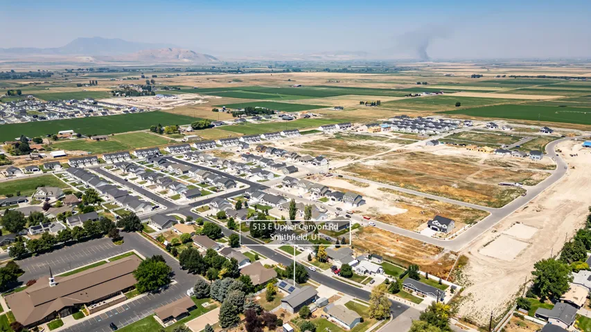 Expansive residential development with a mountain backdrop, surrounded by agricultural fields