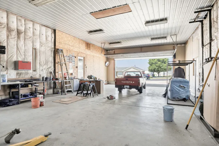 Spacious garage with concrete flooring, exposed ceiling beams, and a large overhead door