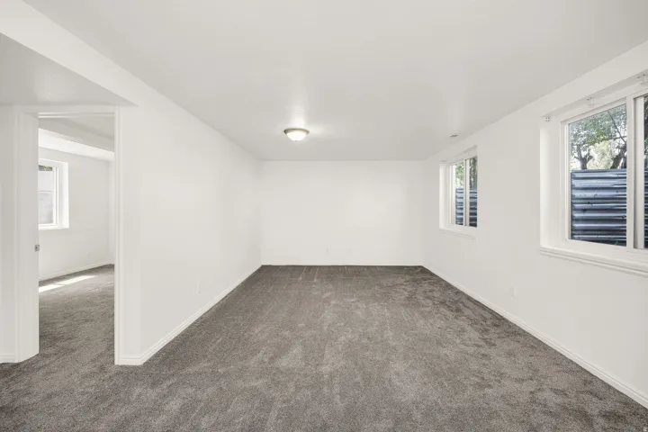 Spacious room featuring neutral carpeting, white walls, and multiple windows